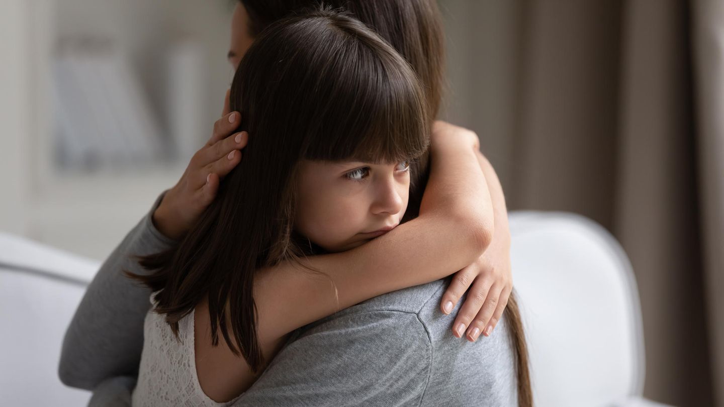 Ein Mädchen umarmt traurig eine Frau.
