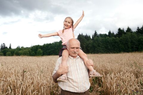 Ein älterer Mann trägt ein Mädchen auf den Schultern