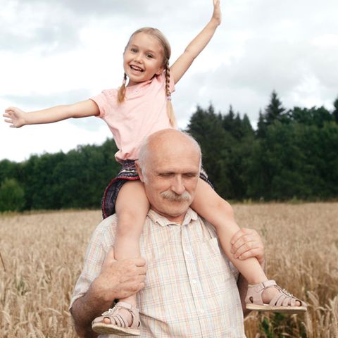 An older man wears a girl on her shoulders