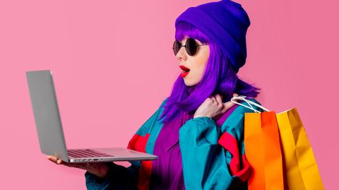 Apple Black Week Deals 2022: Junge Frau mit Laptop lila Haaren und Einkaufstaschen