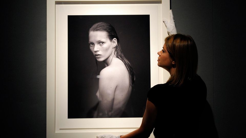 Frau hält ein gerahmtes Portrait von Kate Moss Frau hält ein gerahmtes Portrait von Kate Moss