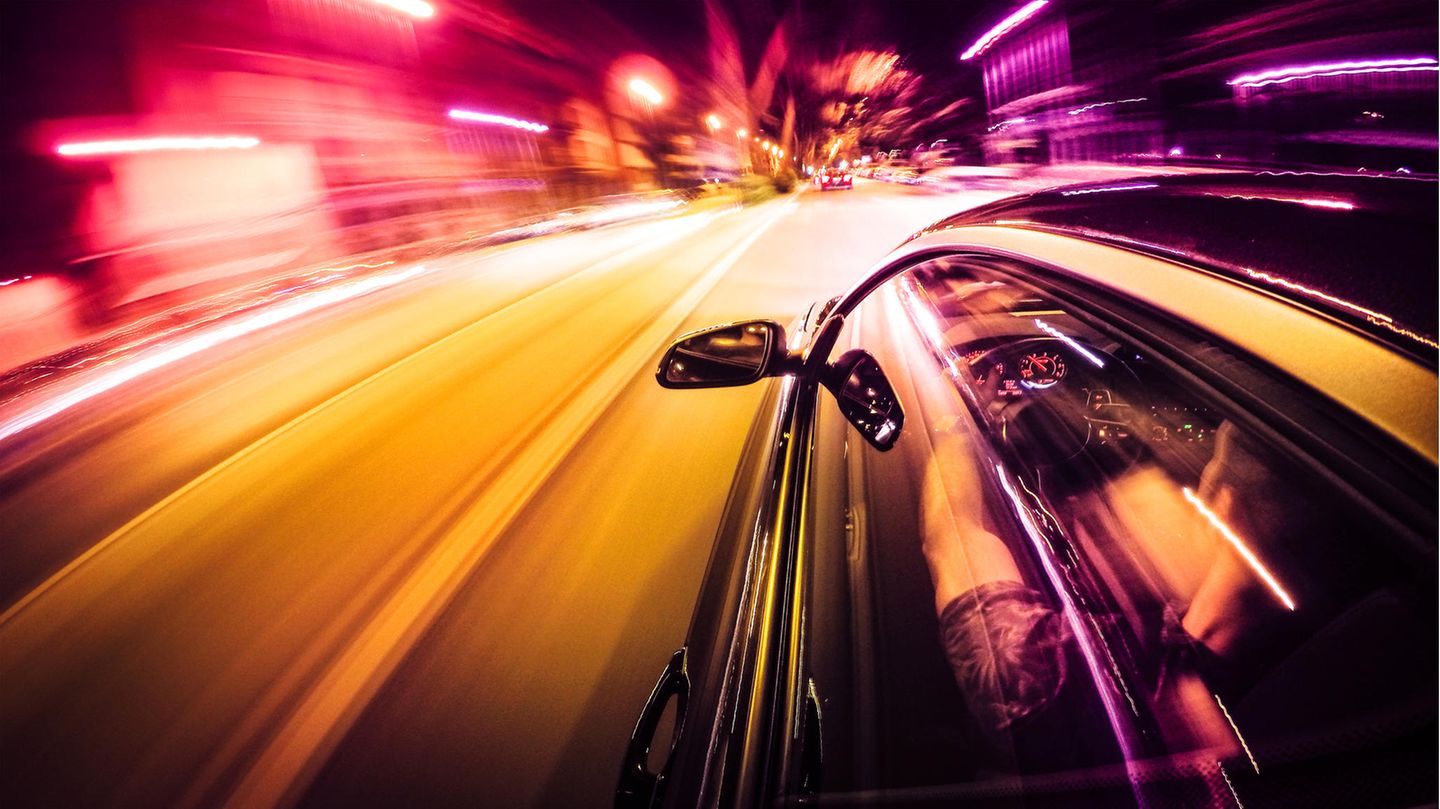 Ein Auto rast durch die Stadt bei Nacht Ein Auto rast durch die Stadt bei Nacht