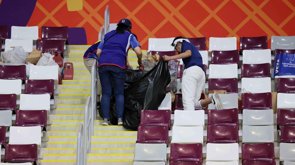 Japanische Fans sammeln Müll im Stadion nach dem Sieg gegen Deutschland