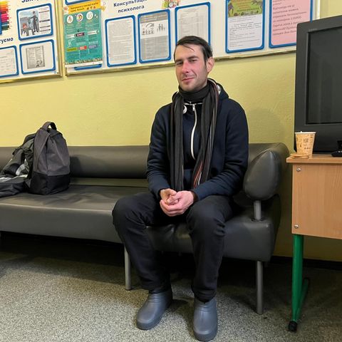 Ruslan wärmt sich in Kyiv in der Eingangshalle einer Schule auf