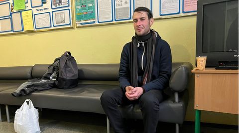Ruslan wärmt sich in Kyiv in der Eingangshalle einer Schule auf