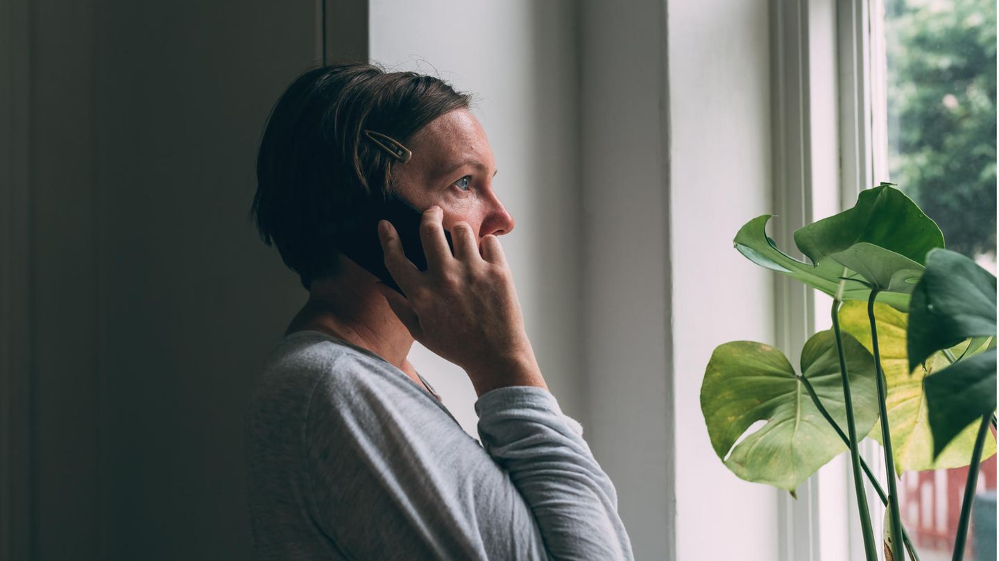 Eine Frau hält sorgenvoll den Telefonhörer in der Hand