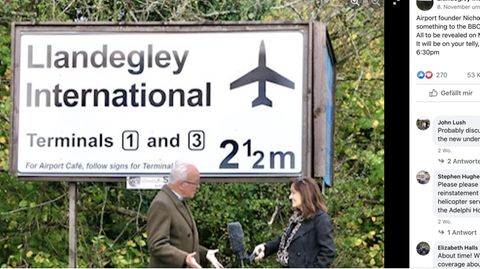 Nicholas Whitehead spricht mit einer BBC-Reporterin vor einem Schild für den fiktiven Llandegley International Airport, Wales