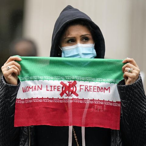 Eine Demonstrantin hält eine Flagge mit der Aufschrift "Women - Life - Freedom"