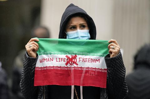 Eine Demonstrantin hält eine Flagge mit der Aufschrift "Women - Life - Freedom"