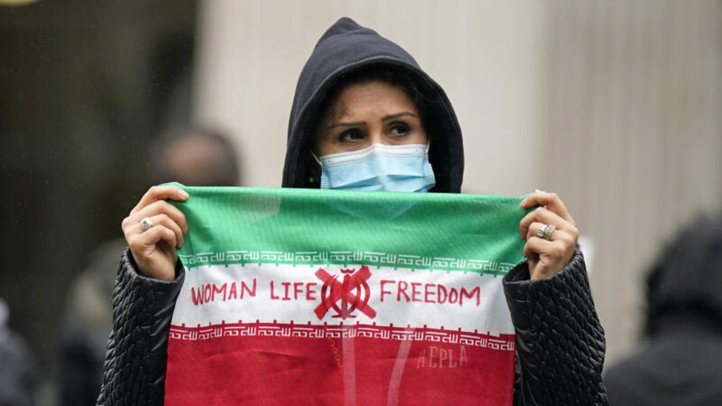 Eine Demonstrantin hält eine Flagge mit der Aufschrift "Women - Life - Freedom"