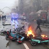 Polizisten gehen an Brand geratenem Müll und Leih-E-Scootern, die mitten auf der Straße in Brüssel liegen, vorbei