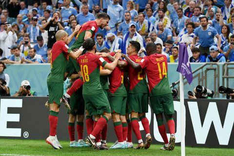 Ein Fußball-Team in rot-grünen Trikots und grünen Hosen jubelt nahe einer Eckfahne