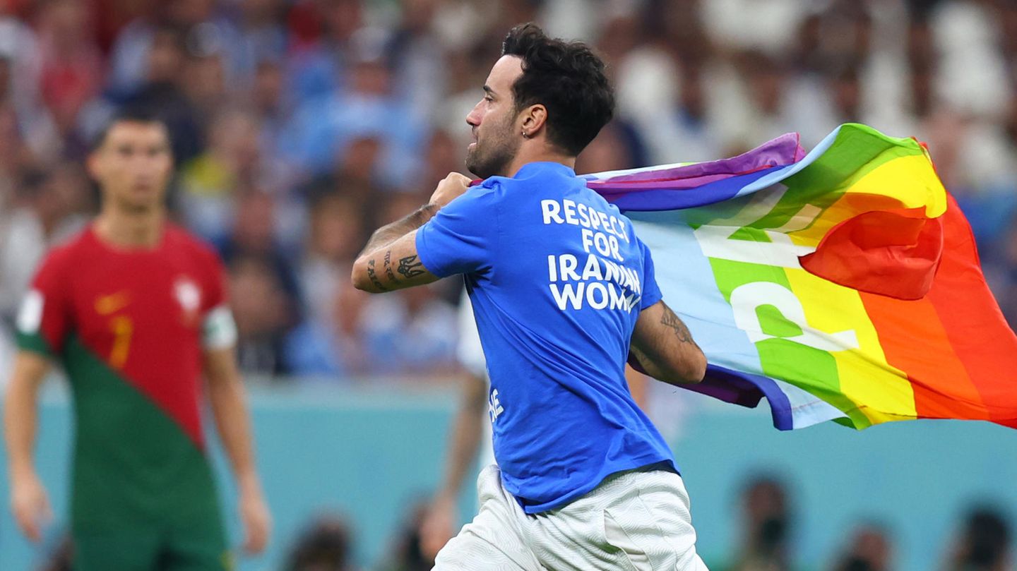 Ein Flitzer mit der Regenbogenflagge läuft über den Rasen des Lusail Iconic Stadions.