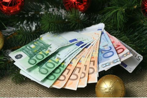 Weihnachtsgeld: Mehrere Geldscheine liegen aufgefächert auf Tannenzweigen und Christbaumkugeln