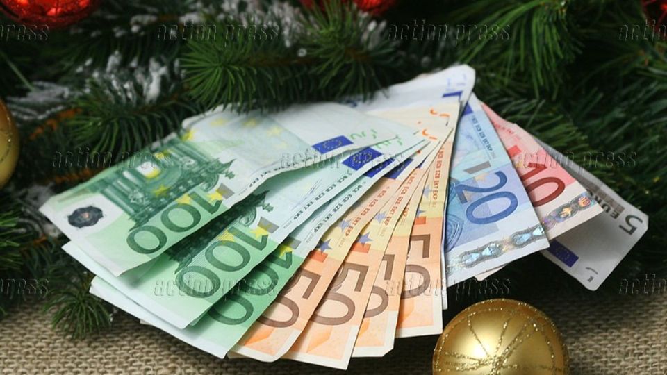 Weihnachtsgeld: Mehrere Geldscheine liegen aufgefächert auf Tannenzweigen und Christbaumkugeln