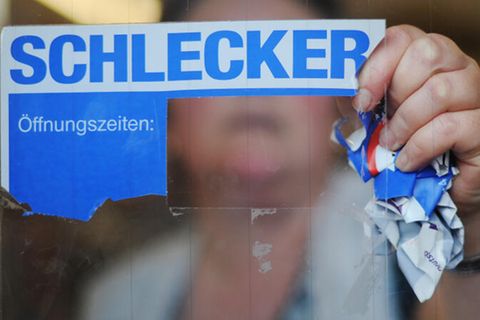 Eine Frau reißt ein Schlecker-Schild ab