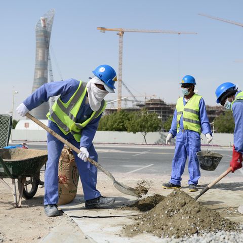 Bauarbeiter aus Sri Lanka arbeiten auf einer Baustelle vor dem Hotel "The Torch" (l) und dem Khalifa International Stadium
