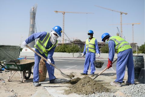 Bauarbeiter aus Sri Lanka arbeiten auf einer Baustelle vor dem Hotel "The Torch" (l) und dem Khalifa International Stadium
