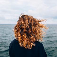 Eine Frau steht vor dem Meer.