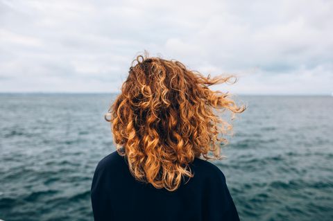 Eine Frau steht vor dem Meer.