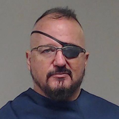 Ein weißer Mann mit Vollbart, Brille und Augenklappe über seinem linken Auge schaut direkt in die Kamera
