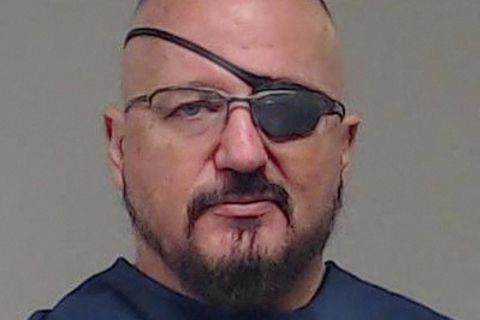 Ein weißer Mann mit Vollbart, Brille und Augenklappe über seinem linken Auge schaut direkt in die Kamera