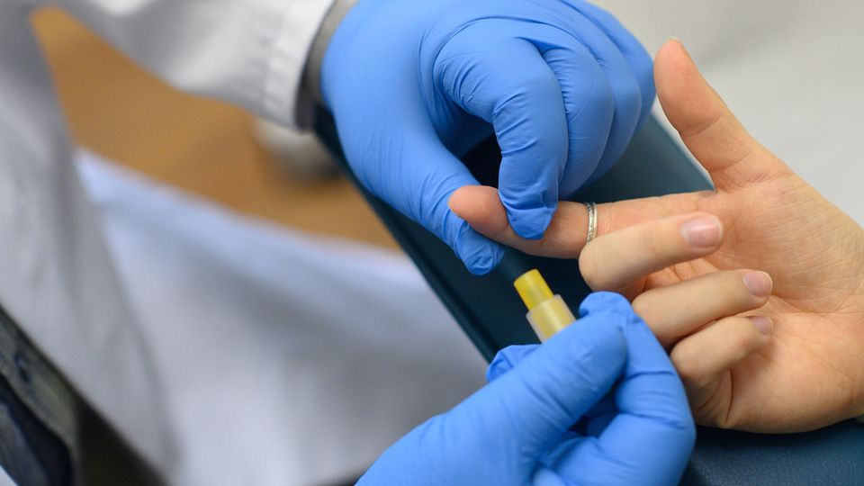 Für einen HIV-Test wird einer Frau am Finger Blut abgenommen