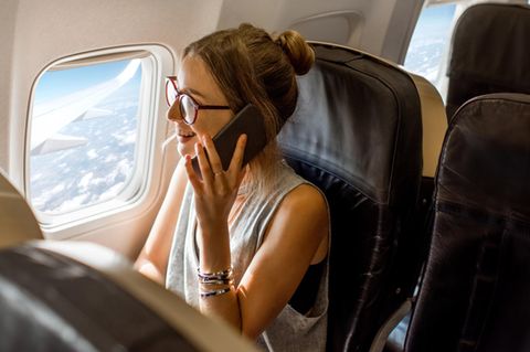 Eine Frau telefoniert an Bord eines Flugzeugs