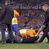 Flitzer liegt auf Rasen vor dem WM-Pokal