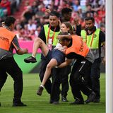 Frau wird von Ordnern weggetragen