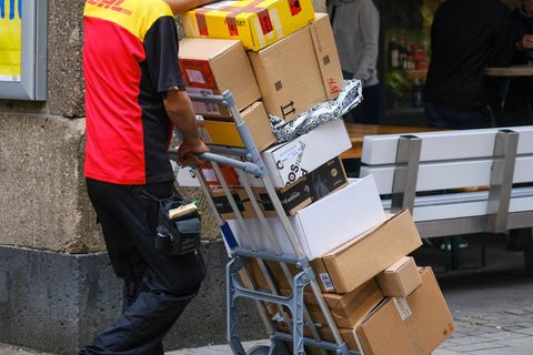Paketbote schiebt auf Sackkarren viele Pakete vor sich her
