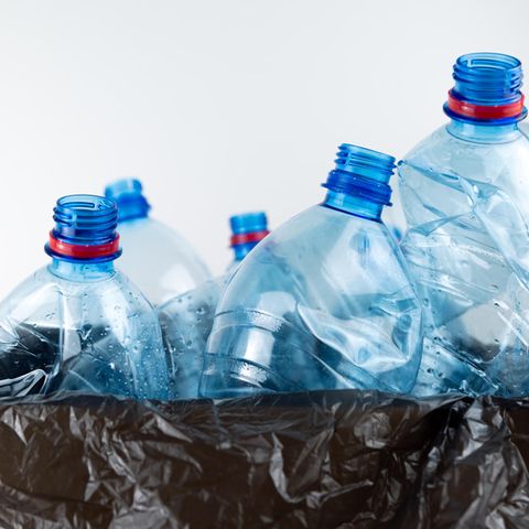 Plastic bottles protrude from black garbage bags