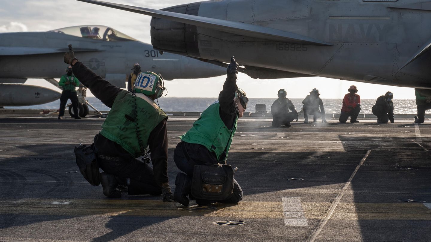 Zwei Personen in grün zeigen den Daumen nach oben. Im Hintergrund zwei Kampfjets.