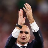 Ein kahlköpfiger weißer Mann im Anzug klatscht mit den Händen über dem Kopf Applaus