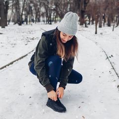 Eine Frau schnürt sich draußen die Schuhe