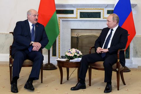 Putin und Lukaschenko stehen nebeneinander und geben sich die Hand