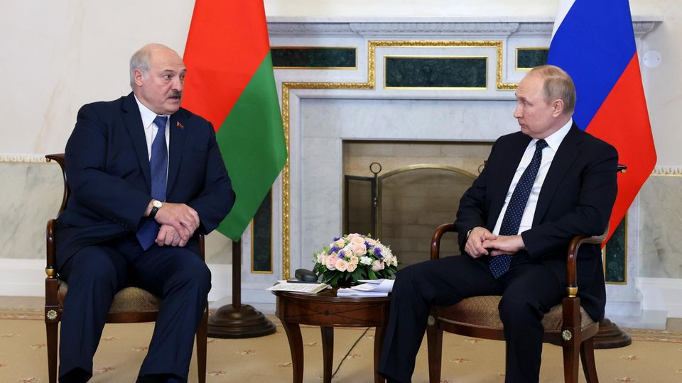 Putin und Lukaschenko stehen nebeneinander und geben sich die Hand