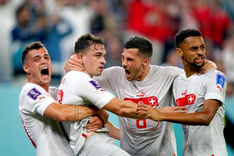 Vier weiße Fußball-Profis in weiß-roten Trikots umarmen sich beim Torjubel