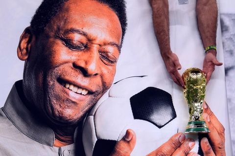 Ein brasilianischer Fan hält eine Nachbildung des WM-Pokals über einem Bild von Pelé.