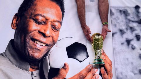 Ein brasilianischer Fan hält eine Nachbildung des WM-Pokals über einem Bild von Pelé.