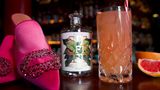 Eine Flasche alkoholfreier Gin, ein Glas Pinky Spicy und pinke Damenschuhe