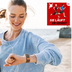 Eine Läuferin am Strand schaut auf ihre Fitness-Uhr
