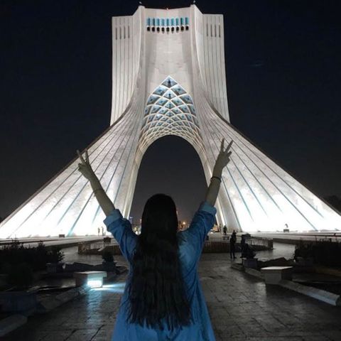 Frau ohne Kopftuch vor dem Azadi Turm in Teheran