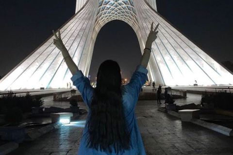 Frau ohne Kopftuch vor dem Azadi Turm in Teheran