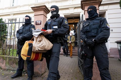 Ein Polizist trägt Tüten, eine Tasche und Papiere