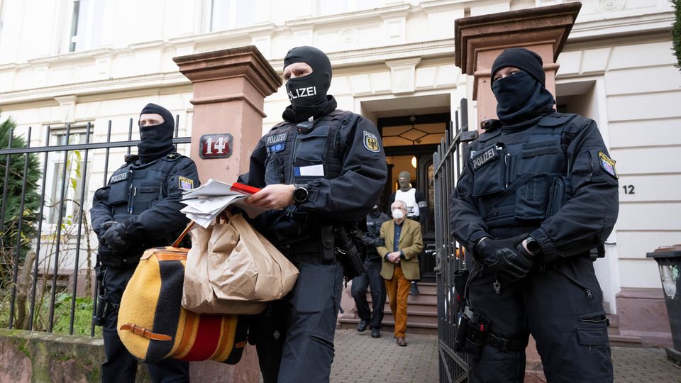 Ein Polizist trägt Tüten, eine Tasche und Papiere
