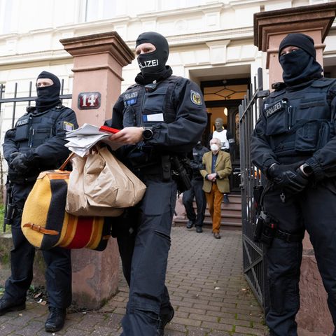 Ein Polizist trägt Tüten, eine Tasche und Papiere