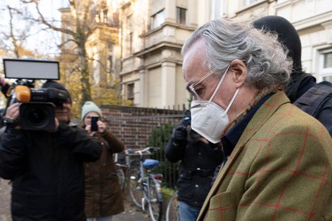 Ein älterer weißer Mann im Jackett und mit zurückgekämmten weißen Haaren wird von vermummten Polizisten abgeführt