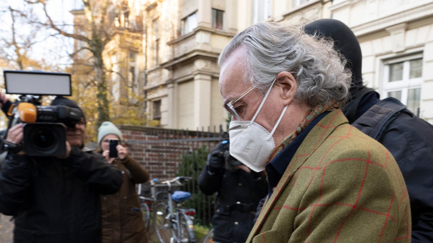 Ein älterer weißer Mann im Jackett und mit zurückgekämmten weißen Haaren wird von vermummten Polizisten abgeführt
