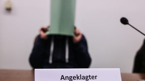 Der Angeklagte im Missbrauchskomplex Wermelskirchen hält sich im Gerichtssaal eine Mappe vor das Gesicht